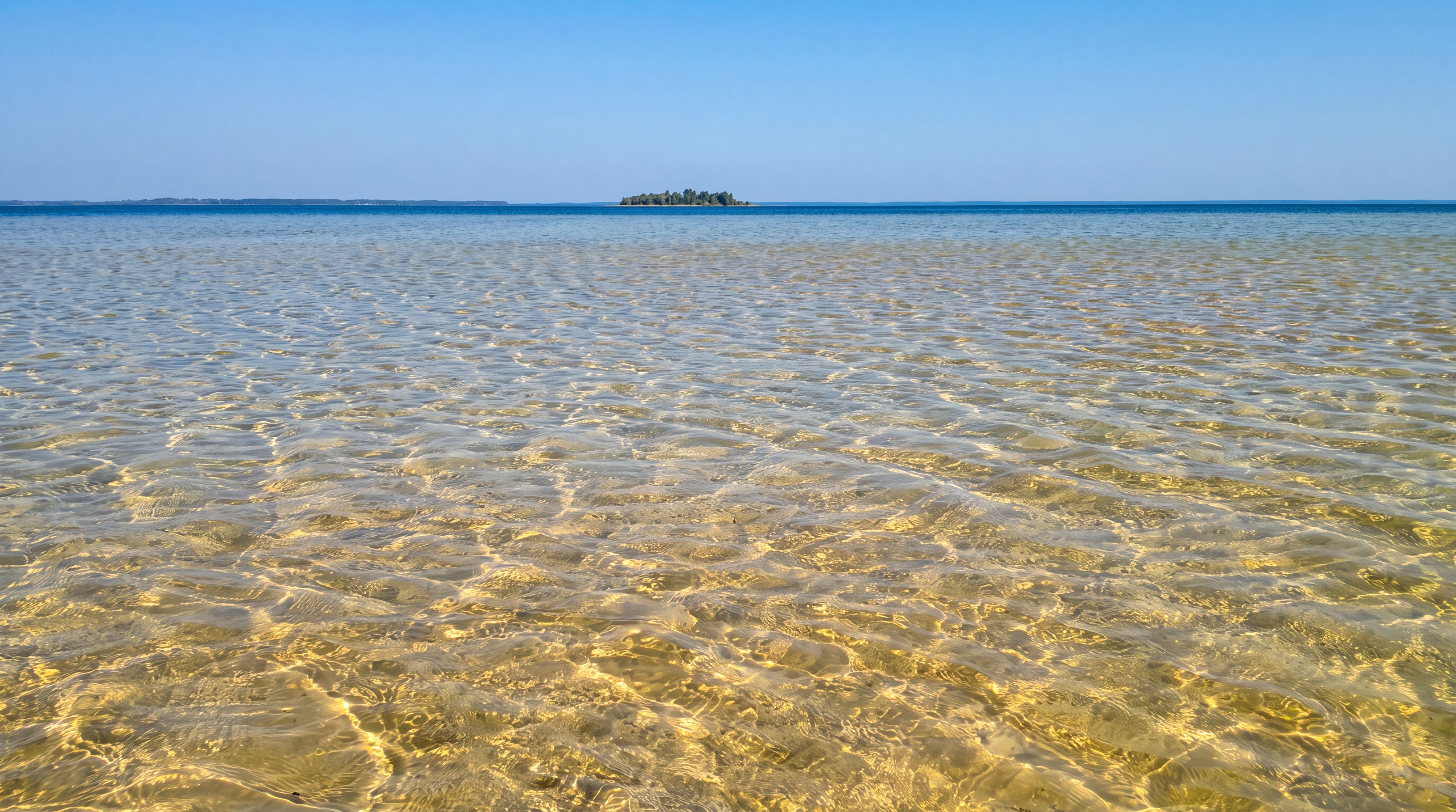 Прозора вода і піщане дно Світязя, на горизонті — острів